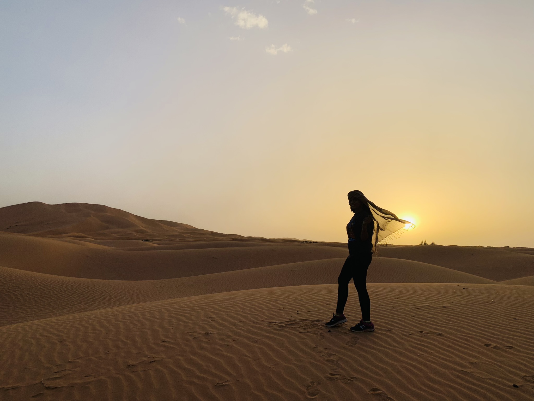Silhouette of dancer in desert at sunset with flowing scarf