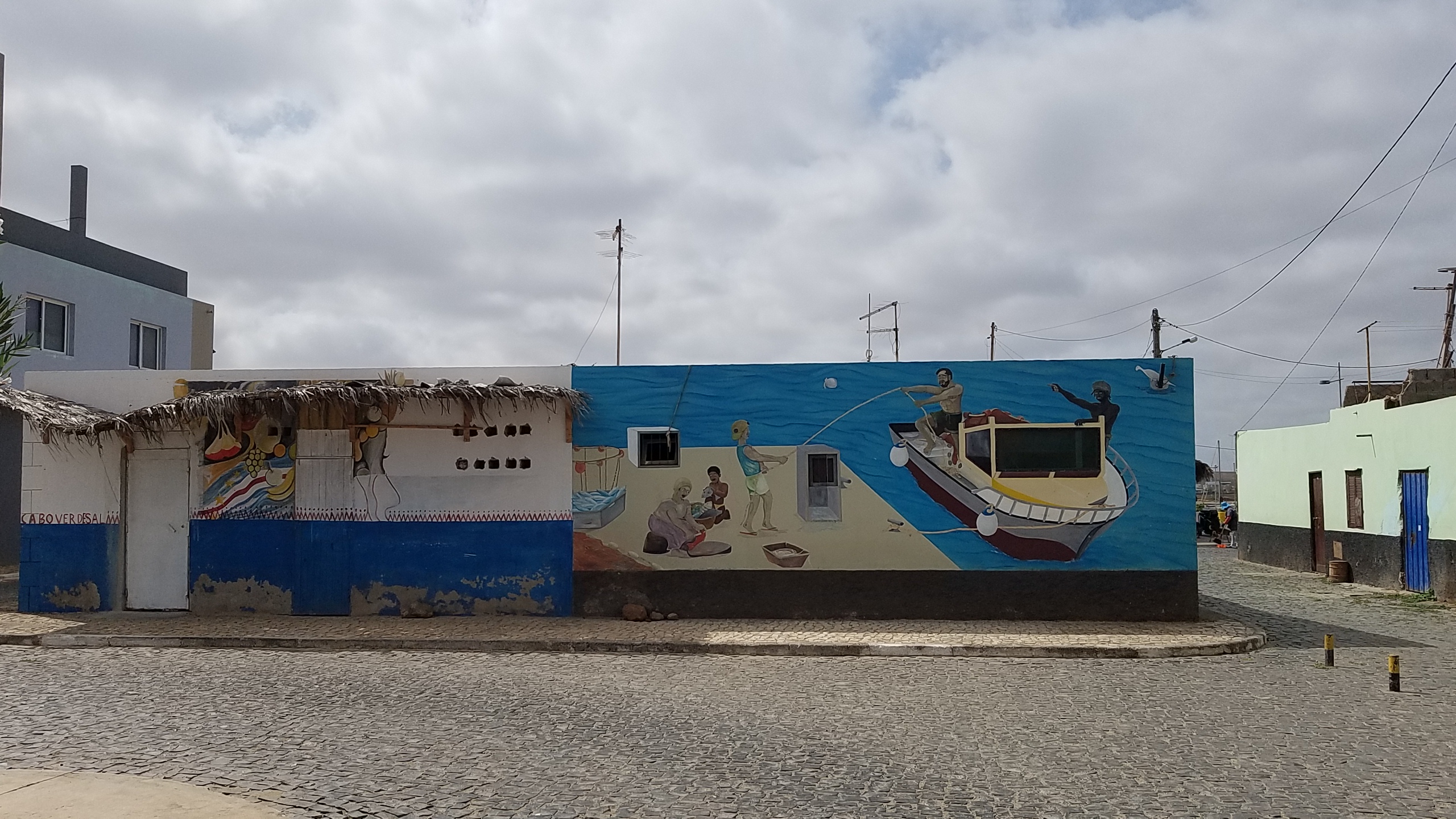 A long street mural in Palmeira, Sal showing fishermen hauling in the day's catch beside a wooden boat
