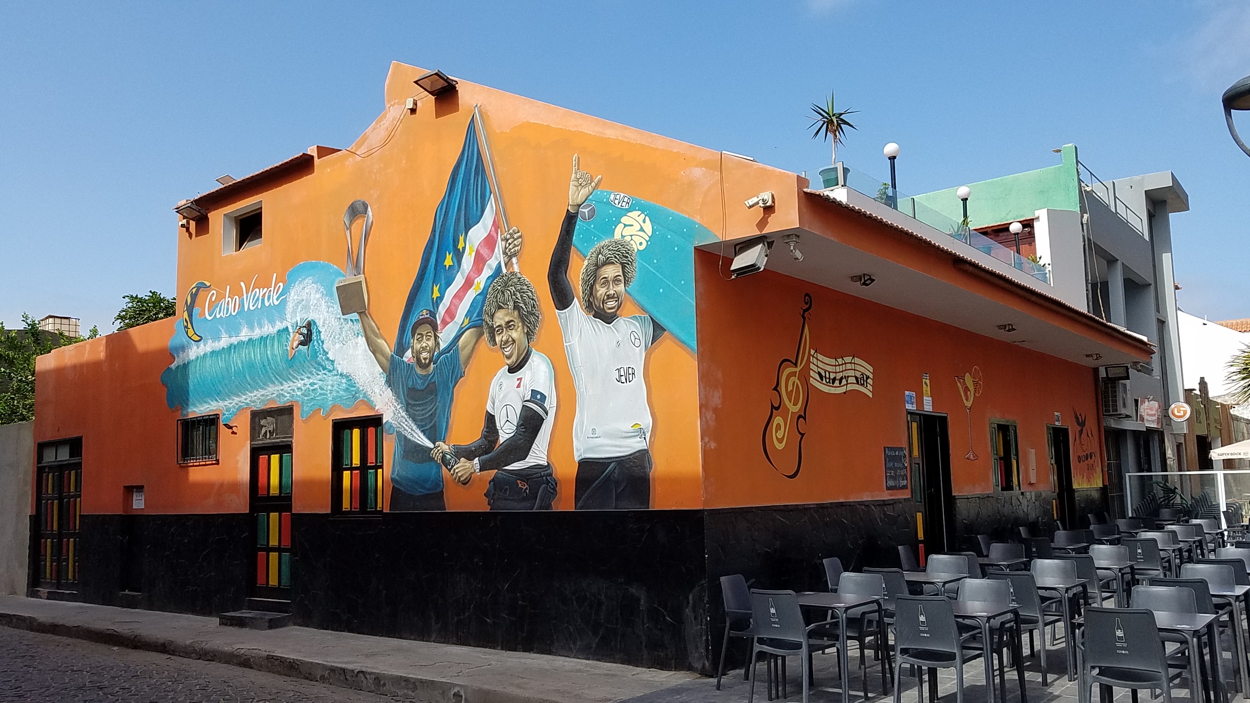 An orange bar in Santa Maria with a mural of Cabo Verde's world-champion surfers holding the national flag